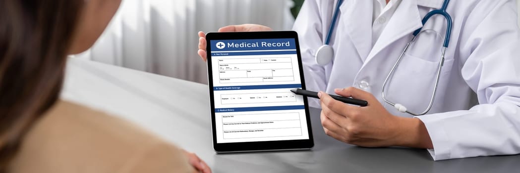 Doctor show medical diagnosis report on tablet and providing compassionate healthcare consultation while being supportive and holding young patient hand in doctor clinic office. Neoteric