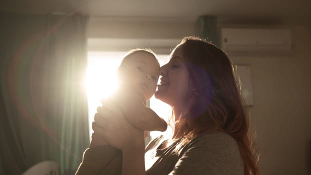 A Caucasian woman tenderly kisses her newborn son in the morning rays of sunlight