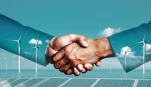 Double exposure graphic of business people handshake over wind turbine farm and green renewable energy worker interface. Concept of sustainability development by alternative energy. uds