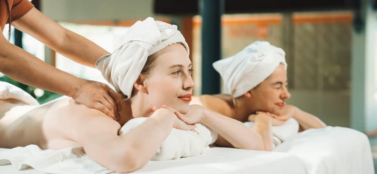 Couple of beautiful young woman lie on white spa bed during having back massage. Attractive caucasian woman having back massage at traditional spa room. Relaxing and healthy concept Tranquility.