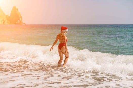 A woman in Santa hat on the seashore, dressed in a red swimsuit. New Year's celebration in a hot country.