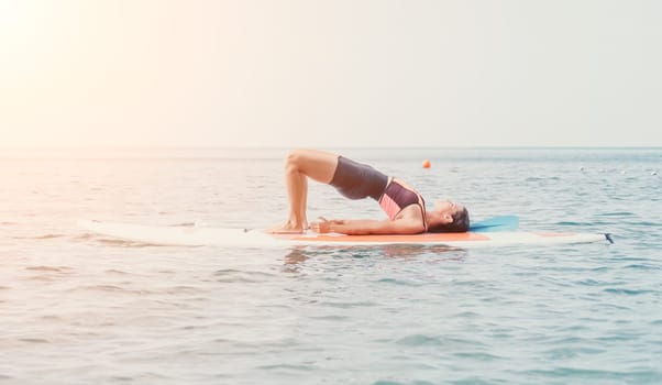 Woman sup yoga. Happy young sporty woman practising yoga pilates on paddle sup surfboard. Female stretching doing workout on sea water. Modern individual female outdoor summer sport activity