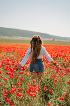 Woman poppies field. Back view of a happy woman with long hair in a poppy field and enjoying the beauty of nature in a warm summer day