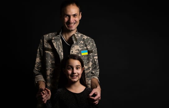 Soldier in military uniform reunited with his family and Ukrainian flag.