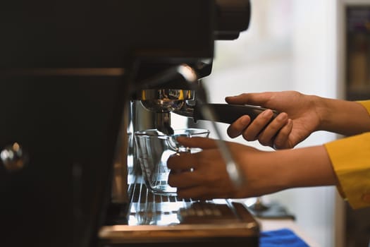 Female barista preparing espresso using coffee machine in a trendy cafe.