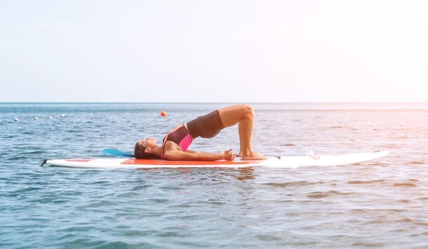 Woman sup yoga. Happy young sporty woman practising yoga pilates on paddle sup surfboard. Female stretching doing workout on sea water. Modern individual female outdoor summer sport activity