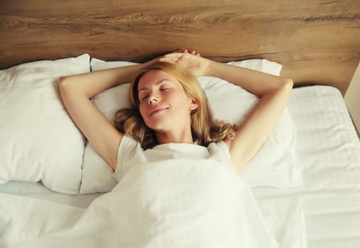 Young woman sleeping lying in bed on white soft comfortable pillow in bedroom at home