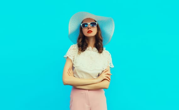 Beautiful caucasian young woman model posing wearing white summer straw hat on blue studio background