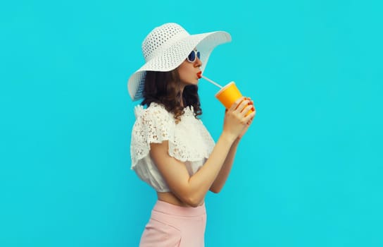 Portrait of beautiful caucasian young woman model with cup of coffee or fresh juice wearing white summer straw hat on studio blue background