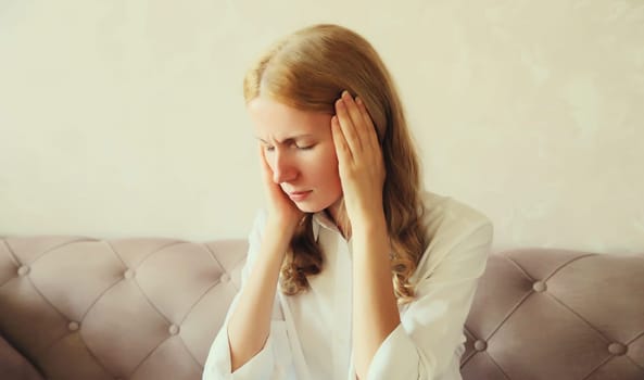 Exhausted tired caucasian young woman employee with headache or temples pain, suffers from migraine, tension in the head at home