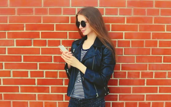 Modern caucasian young woman 20s model with mobile phone looking at device on city street