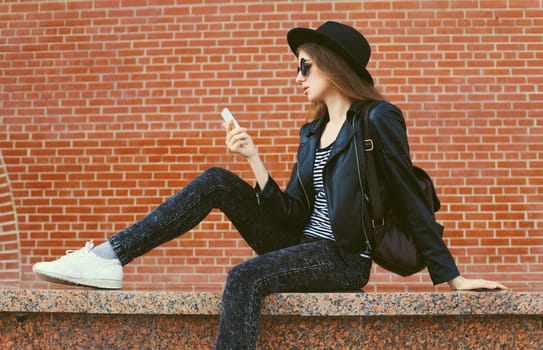 Modern caucasian young woman 20s model with mobile phone looking at device on city street