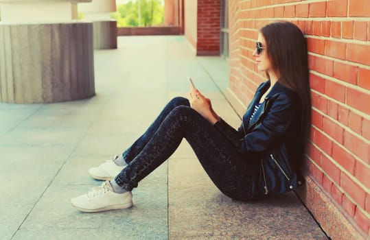 Modern caucasian young woman 20s model with mobile phone looking at device on city street
