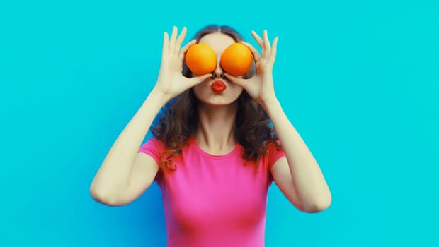 Summer, nutrition, diet and vegetarian concept. Happy healthy cheerful young woman covering her eyes with slices of orange fruits and looking for something on blue background