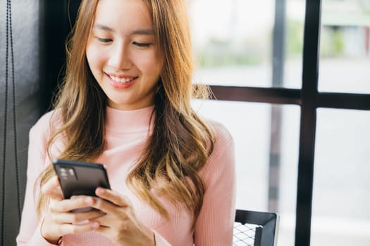 Asian young woman hands holding mobile phone at cafe coffee shop, Happy beautiful female typing text message on smart phone device and enjoyment lifestyle with social networking media