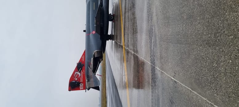Turkish F-4 Phantom fighter jet parked on a rainy day, its formidable presence underscored by the relentless downpour, capturing a moment of quiet strength.