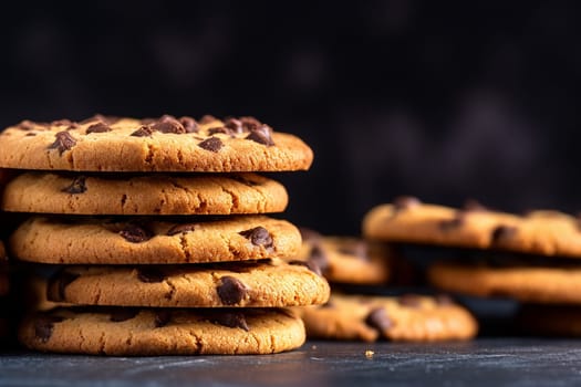 Stack of chocolate chip cookies on a dark surface.