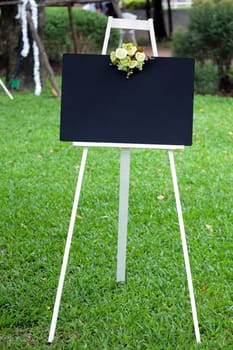 Blank black board with flower on the stand in the garden.