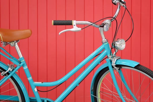 Blue vintage bicycle on red wooden wall background, close up of bicycle