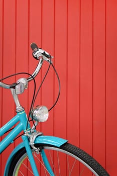 Blue vintage bicycle on red wooden wall background, close up of bicycle