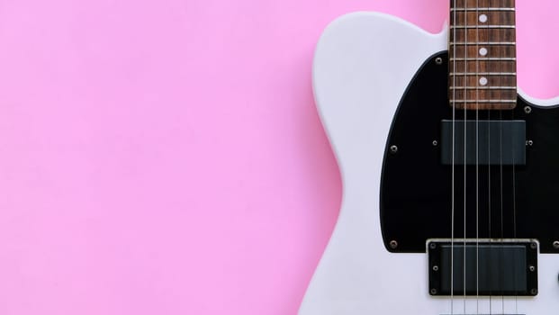 Black and white electric guitar on a pink background. Top view.