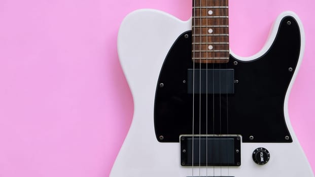 Black and white electric guitar on a pink background. Top view.