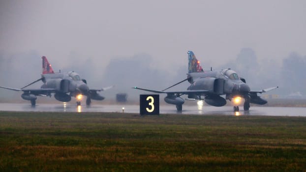 NATO fighter jets taxiing to takeoff under intense rain. highlighting the alliance readiness and the dramatic weather. McDonnell Douglas F-4 Phantom II of Turkish Air Force. Copy space.