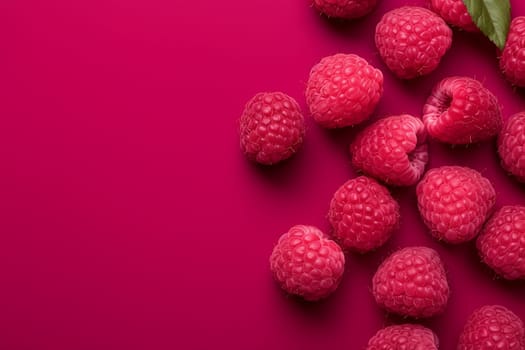 A cluster of fresh raspberries on a vibrant pink background.