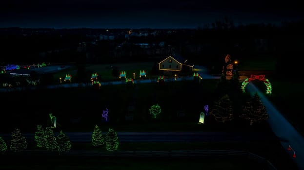 Twilight Scenery With Illuminated Christmas Decorations, Row Of Trees Wrapped In Lights, And A Lit House Against A Dusky Sky.