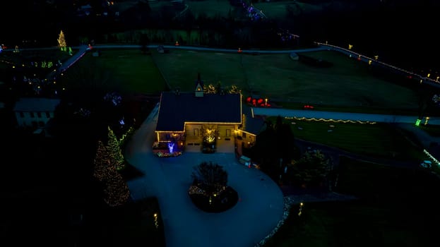 Bird's-Eye View At Night Showcasing A Building With Bright Christmas Lights And A Tree-Lined Driveway In A Dark Rural Setting.