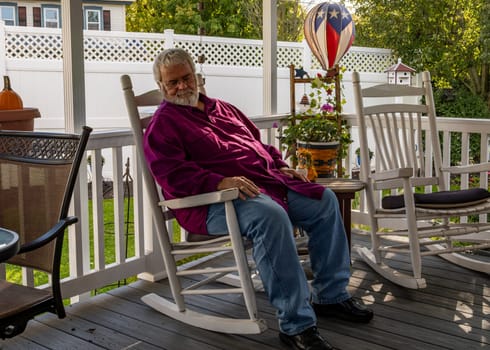 A Senior Aged Male Sleeping in a Rocking Chair, on a Deck, Enjoying His Retirement After Thanksgiving Dinner