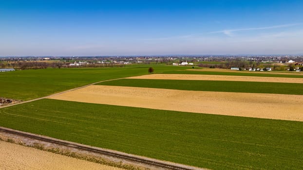 Vast Agricultural Fields With Distinctive Green And Beige Patterns Bordering A Small Town Under The Expansive Blue Sky.