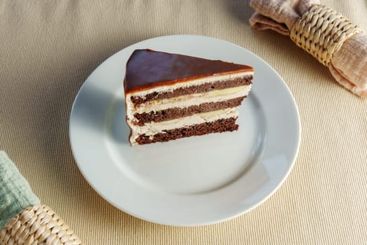 Slice of rich, moist chocolate cake delicately balanced on top of a pristine white plate.