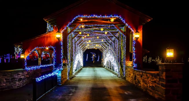 Twinkling Blue And White Lights Line The Interior Of Herr's Mill Covered Bridge From 1844, Creating A Festive Tunnel Effect At Night, With A Sign Displaying The Name And Date.