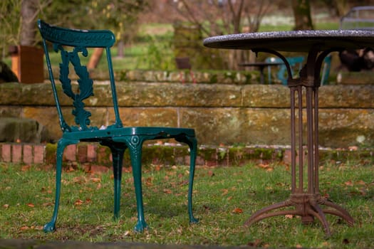 A green chair sits next to a table in the grass. High quality