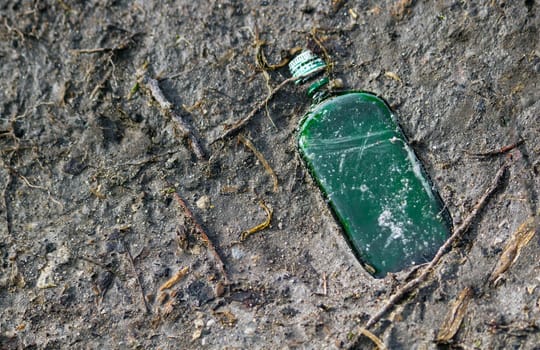 A green bottle is laying on the ground. High quality.