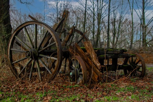 An old wooden wagon wheel is sitting in the grass. High quality