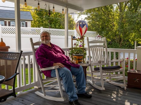 A Senior Aged Male Resting in a Rocking Chair, on a Deck, Enjoying His Retirement on a Autumn Day