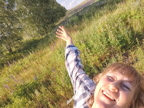 Happy female blonde tourist taking selfie picture with smart mobile phone outside. Middle aged woman having fun on adventure nature trip on nature