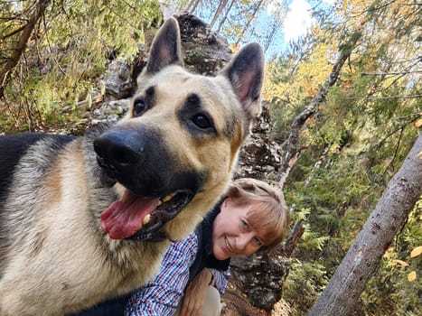 Adult girl with shepherd dog taking selfies in forest. Middle aged woman and big shepherd dog on nature. Friendship, love, communication, fun, hugs