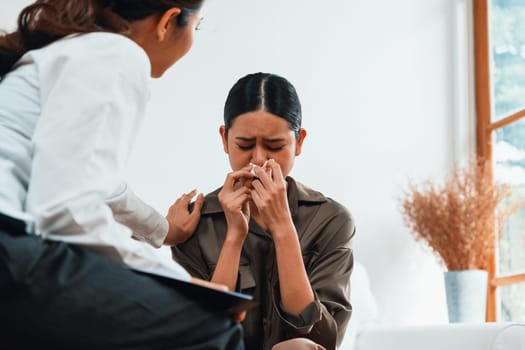 Sad PTSD woman patient in uttermost therapy for mental health with psychologist, depression or grief after life failure. Frustrated trauma young woman talking to a psychologist about emotion in clinic