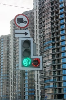 Green traffic light and road signs against tall building close up