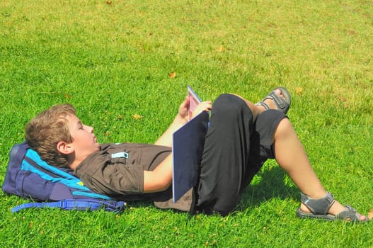 The boy, after school, lay on the grass and reading a book