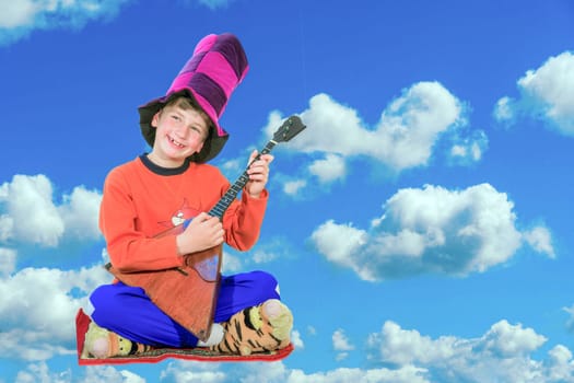 Little Harlequin with a balalaika sits on the carpet and soars in the clouds