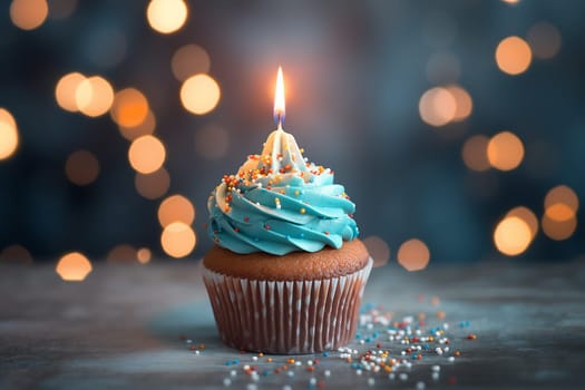 A single cupcake with blue icing and a lit candle against a bokeh background