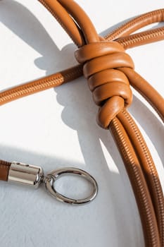 Brown genuine leather bag strap or handbag handle isolated on white background. High-quality material with a unique knot design adds style and elegance to your bag. Perfect accessory for any occasion.