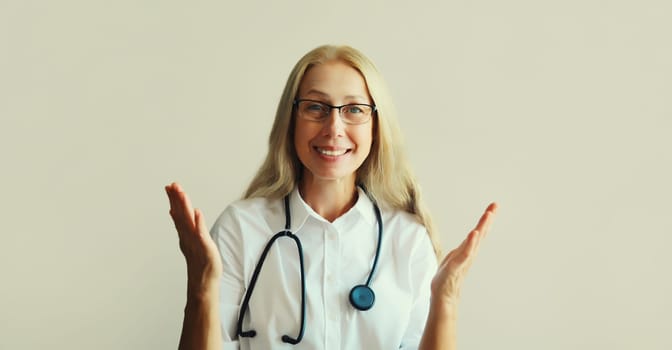 Modern caucasian middle-aged woman doctor looking at camera talking on video call sitting at desk in clinic office