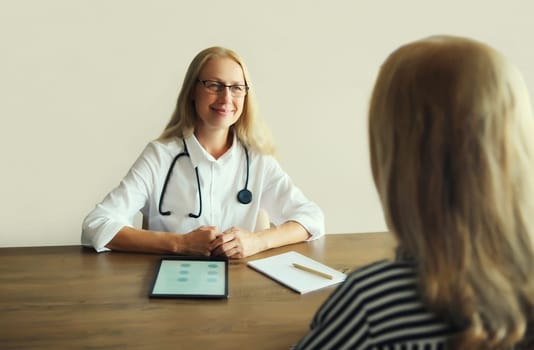 Patient at doctor's appointment. Caucasian middle-aged woman doctor therapist talking to the girl prescribes medications while sitting at table in clinic office