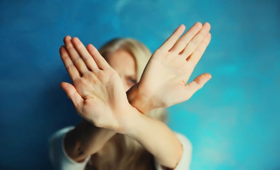 Upset young woman shows stop, no or enough sign with palm of hand, refusal gesture, domestic violence