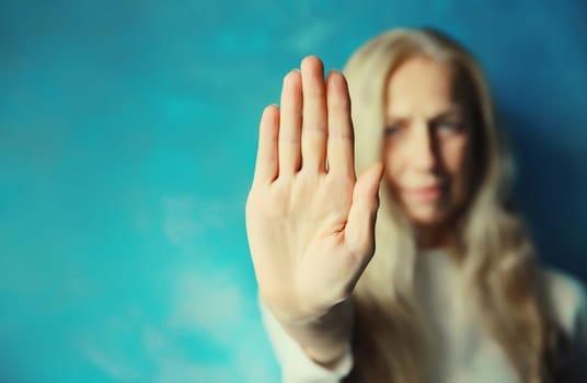 Upset young woman shows stop, no or enough sign with palm of hand, refusal gesture, domestic violence